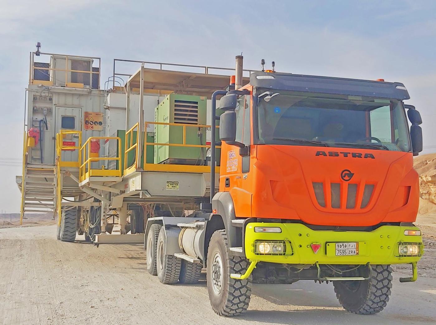Orange Astra 6x6 oilfield tractor hauling a rig component through the desert